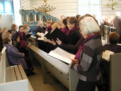 Seurakunnan lauluryhmä esiintyi kirkon penkissä ehtoollisen aikaan.